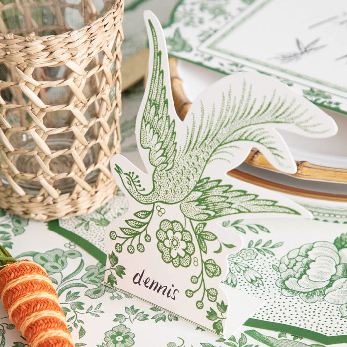 A Green Asiatic Pheasants Place Card designed by Hester & Cook, featuring a bird and carrots, is placed to make guests feel welcomed.