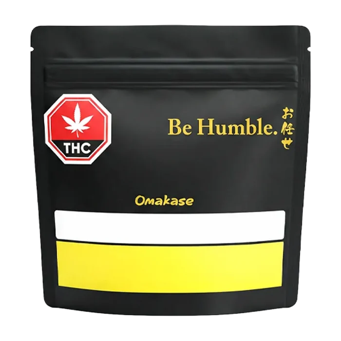 Front-facing shot of the black pouch labeled "Omakase" with gold "Be Humble." text and a red THC symbol.