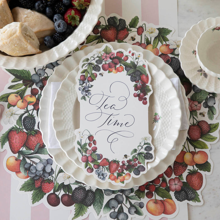 A Berry Bramble Table Card with "Tea Time" written on it in beautiful script resting on the plate of a summertime place setting, from above.