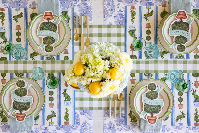 Table setting with a floral centerpiece, Spring Topiary Placemats, Topiary Table Accents, Green Icing on the Cake Plates, seafoam napkins and cutlery on the Moss Painted Check and Blue Regal Peacock Runners.