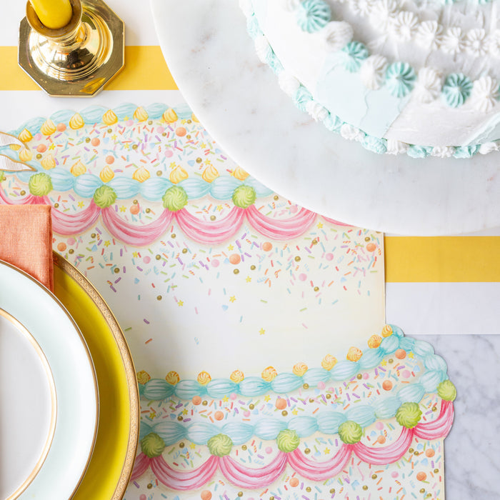 Dining table setting with Die-cut Birthday Cake Placemat, colorful dinnerware, decorative cake and a candle on the Marigold Classic Stripe Runner.