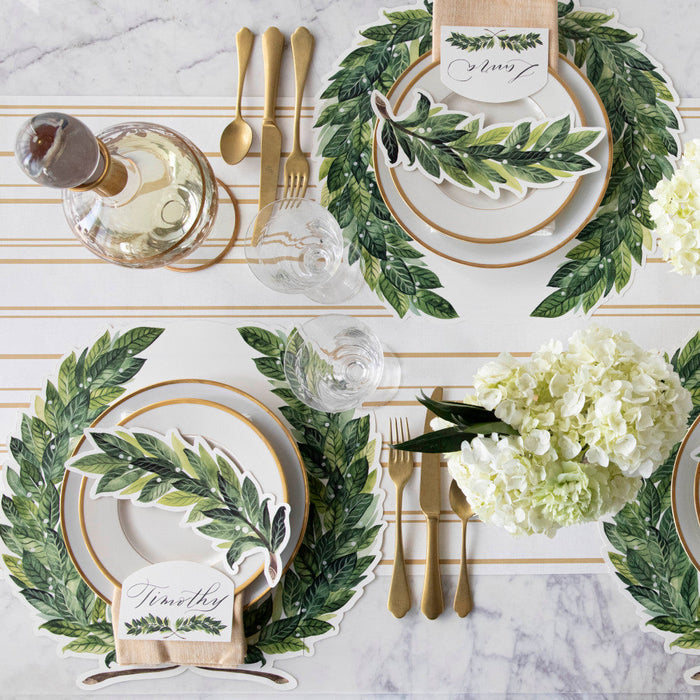 The Die-cut Green Laurel Wreath Placemat under an elegant table setting for four, from above.