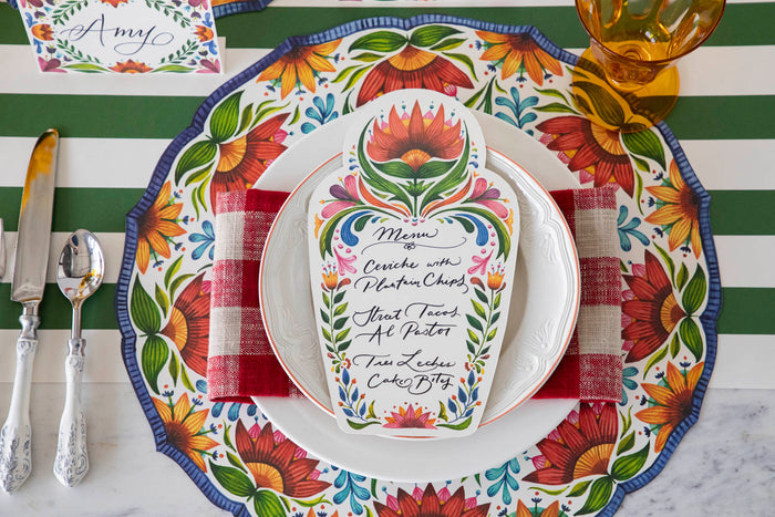 A vibrant place setting featuring a Fiesta Floral Table Card with a menu written on it in beautiful script resting on the plate.
