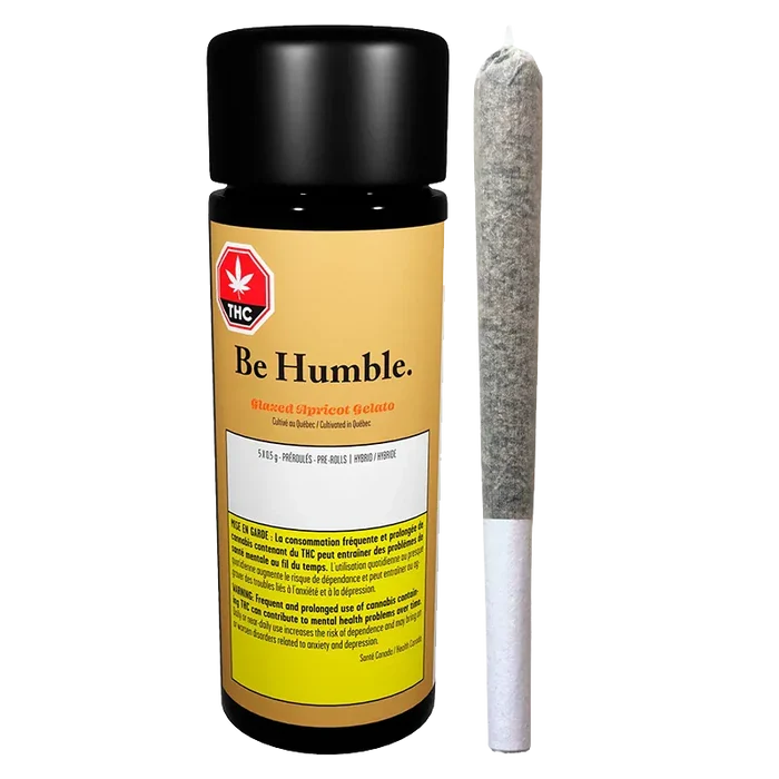 Front-facing shot of a black-capped jar labeled "Be Humble. Glazed Apricot Gelato PR 5 x 0.5 g" standing next to a single pre-rolled joint on a white background.