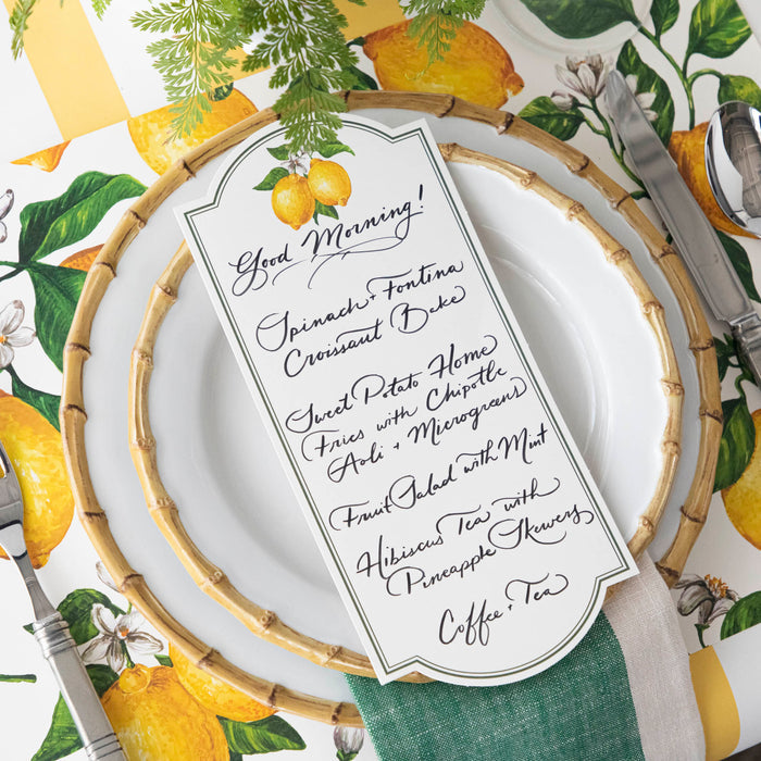 A bright citrus-themed place setting featuring a Lemon Table Card with a menu written on it resting on the plate.