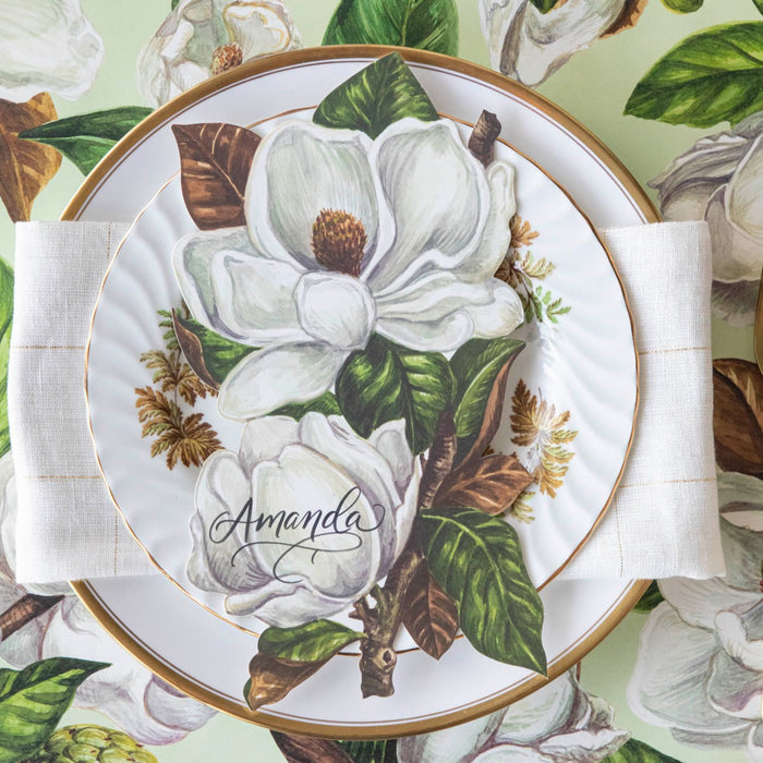 An elegant place setting featuring a Magnolia Blooms Table Accent with "Amanda" written in beautiful script resting on the plate.