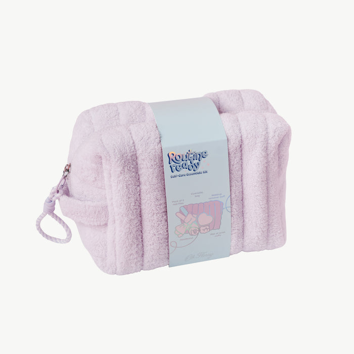 A light lilac plush cosmetic bag with a matching zipper pull and a light blue paper band label wrapped around the center, photographed on a clean off-white background.