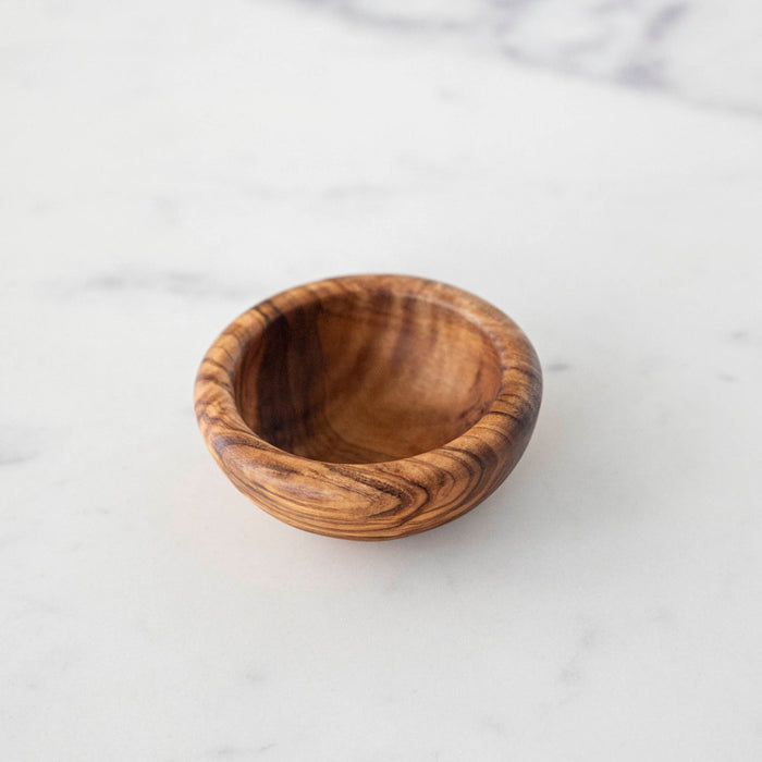 A Natural Olivewood Pinch Bowl on a white table.