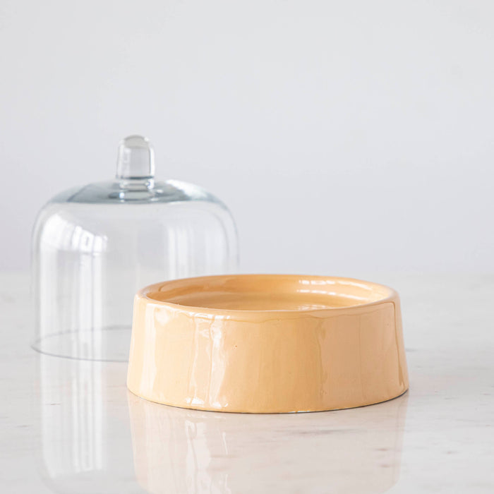 A Petite Sweet Cake Dome in the color sherbert with the lid removed atop a white marble surface.