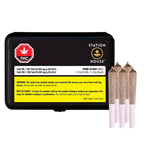 Front-facing shot of a black Station House Pink Kush PR 5 x 0.5 g tin with a yellow warning label and three pre-rolls standing beside it.
