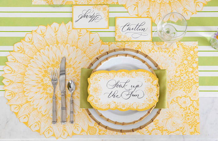 A Spring Blooms Table Card with "Soak up the sun" written on it in lovely script resting on the plate of a vibrant place setting.